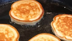 four pancakes cooking in a skillet on top of a stove burner with oil