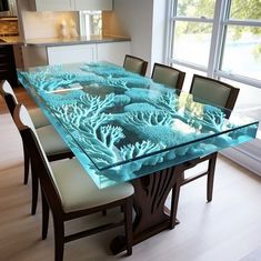 a glass table with blue corals on it in front of a window and chairs