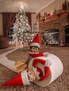 an elf is sitting on top of a roll of toilet paper in front of a christmas tree