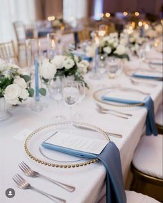 the table is set with silverware and blue napkins for an elegant wedding reception