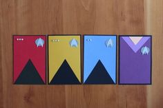 four pieces of paper cut out to look like spaceships on a wooden surface, each with different shapes and sizes