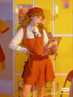 a woman in an orange dress is holding a book and standing next to a yellow wall