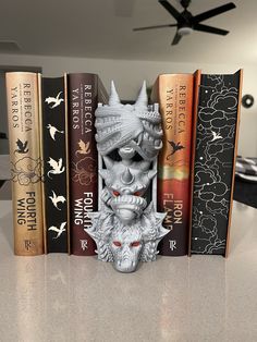 a row of books sitting next to each other on top of a counter in front of a ceiling fan