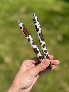 two white and brown pens in the palm of someone's hand