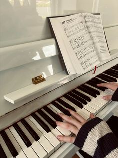 two hands are playing the piano with sheet music