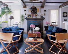 a living room filled with blue couches and wooden chairs next to a fire place