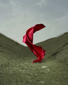 a red cloth blowing in the wind on a grassy hill