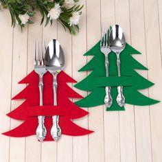 two forks and spoons are sitting next to each other in front of a christmas tree