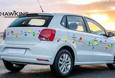 the back end of a white car with christmas lights on it