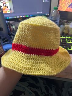 a person wearing a yellow and red crochet hat with a red ribbon around the brim