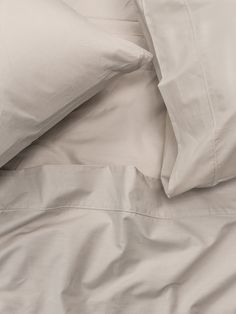 an unmade bed with white sheets and pillows