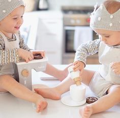 two toddlers are sitting on the table playing with their toys and making donuts