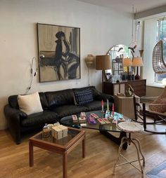 a living room filled with furniture and a painting on the wall above it's coffee table