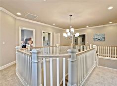 a staircase in a house with white railings and chandelier hanging from the ceiling