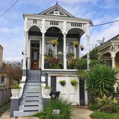 an old victorian house with potted plants on the porch and steps leading up to it