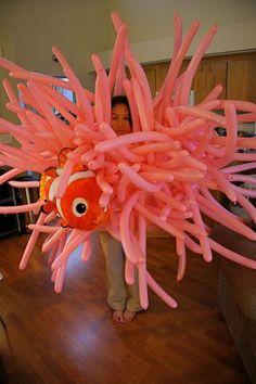 a woman holding an inflatable blow up fish on top of a hard wood floor