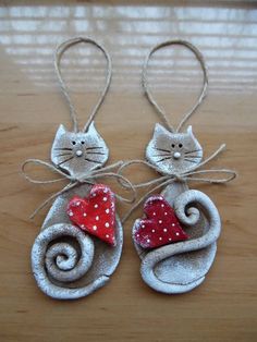 two ornaments made to look like cats with hearts