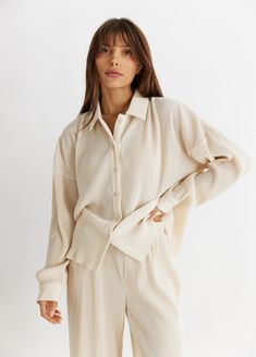 catch flights AND feelings in this elevated, yet oh so cozy crinkle top. elevate the look by pairing it with the aspen bottoms to create the dreamiest set you've ever laid eyes on. whether you're at the airport or enjoying a cozy new year's eve in, all eyes will be on you as you find the perfect balance between cozy + cute. oversized, long sleeve, crinkle textured pleated button-front knit top with pointed collar + raw cut hem detailing 95% polyester, 5% spandex style runs with a slightly relaxe Trip Clothes, Pleated Knit, Crinkle Top, Sunken Living Room, Shirt Pant Set, Button Long Sleeve, Button Front Top, Chic Top, Pleated Fabric