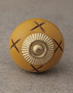 a yellow door knob with crosses painted on the front and back side, sitting on a gray surface