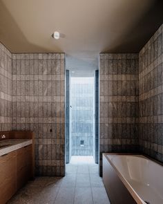 an empty bathroom with a bathtub and sink next to a large window in the wall