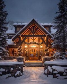 a large house with snow on the ground and trees in front of it at night