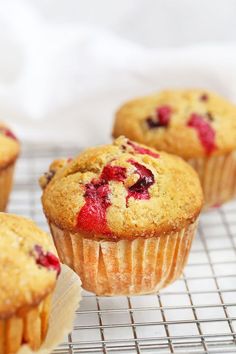 muffins cooling on a wire rack with cranberries and strawberries in them