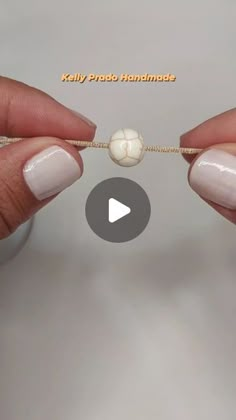 two hands holding a string with beads attached to it, and the video below shows how they are making beaded bracelets