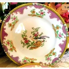 an old china plate with flowers and birds painted on the side, sitting on a table