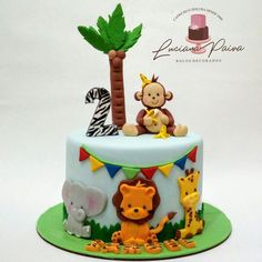 a birthday cake decorated with animals, giraffes and palm trees