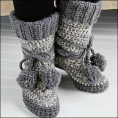 a pair of crocheted gray boots with pom - poms