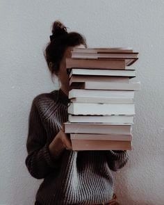 a woman holding a stack of books in front of her face