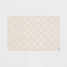 a white bath mat with squares on the front and back of it, against a white background