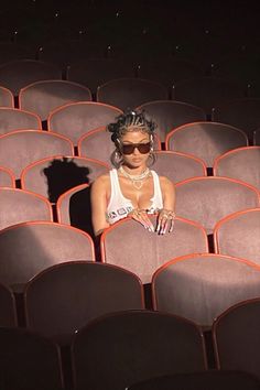 a woman sitting in the middle of rows of chairs with her hands on her hips