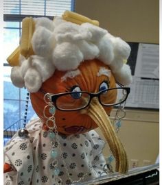 an orange with white hair wearing glasses and a wig