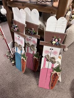 three wooden rabbits are standing next to each other in front of a table with flowers on it