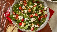 a salad with spinach, tomatoes and feta cheese in a bowl on a table