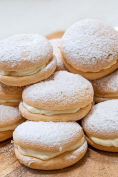 a pile of powdered sugar covered cookies sitting on top of a wooden cutting board