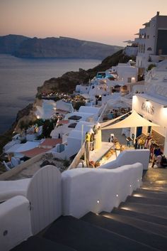 people are walking up the stairs to an outdoor restaurant on the cliff overlooking the ocean