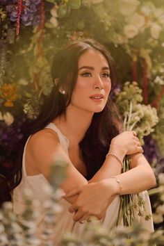 a woman standing in front of flowers with her arms crossed