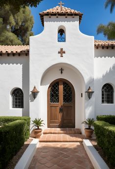 a white church with a wooden door and cross on the front entrance, surrounded by greenery