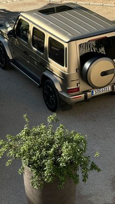 an suv is parked on the street next to a potted plant