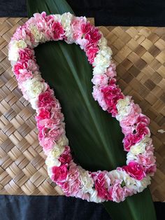 pink and white carnations arranged in a heart shape on a bamboo mat background