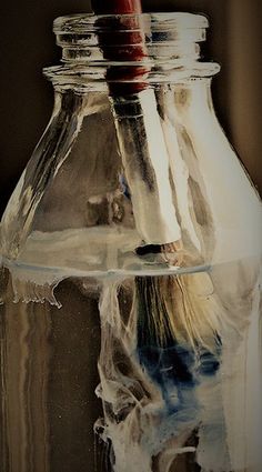 a glass jar filled with water and a toothbrush