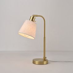 a gold lamp with a white shade on the base and a cord attached to it