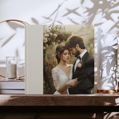 a wedding photo is placed on a table next to a vase with flowers in it