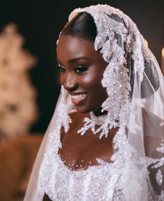 a woman in a wedding dress smiles at the camera while wearing a bridal veil