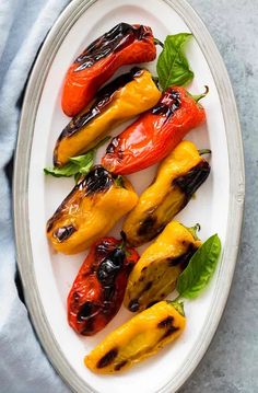 grilled peppers on a plate with basil leaves