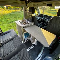 the interior of a vehicle with a table and sink in the back seat, next to an open car door