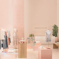 a room filled with different types of clothing on display in front of a pink wall