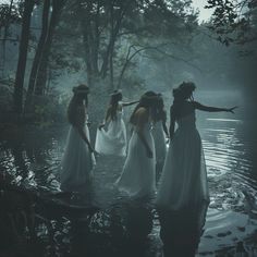 four women in white dresses are standing in the water with their arms out to each other